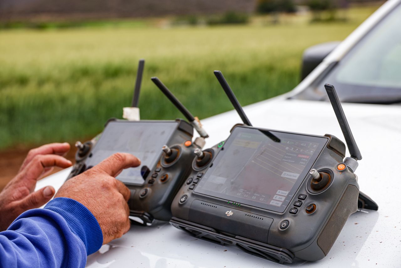 services-04 Close-up of farmers using drone controllers on a farm for precision agriculture.